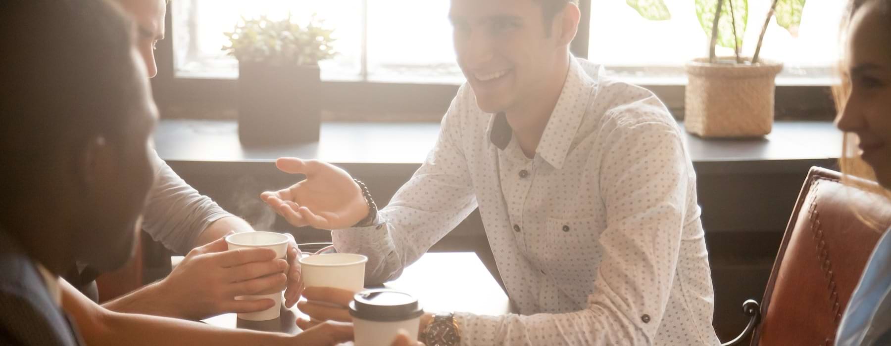 a group of people sitting around a table with coffee cups
