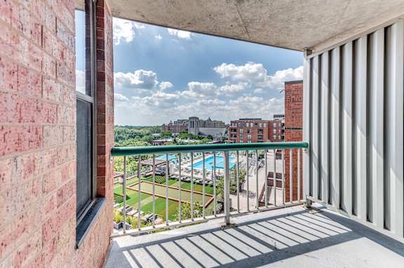 A balcony with a view of a pool and buildings.