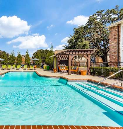 A large outdoor swimming pool with a sun lounger and umbrella.
