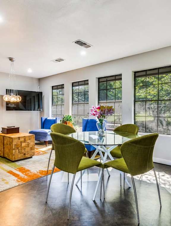 A living room with a blue chair, a green chair, and a wooden table.