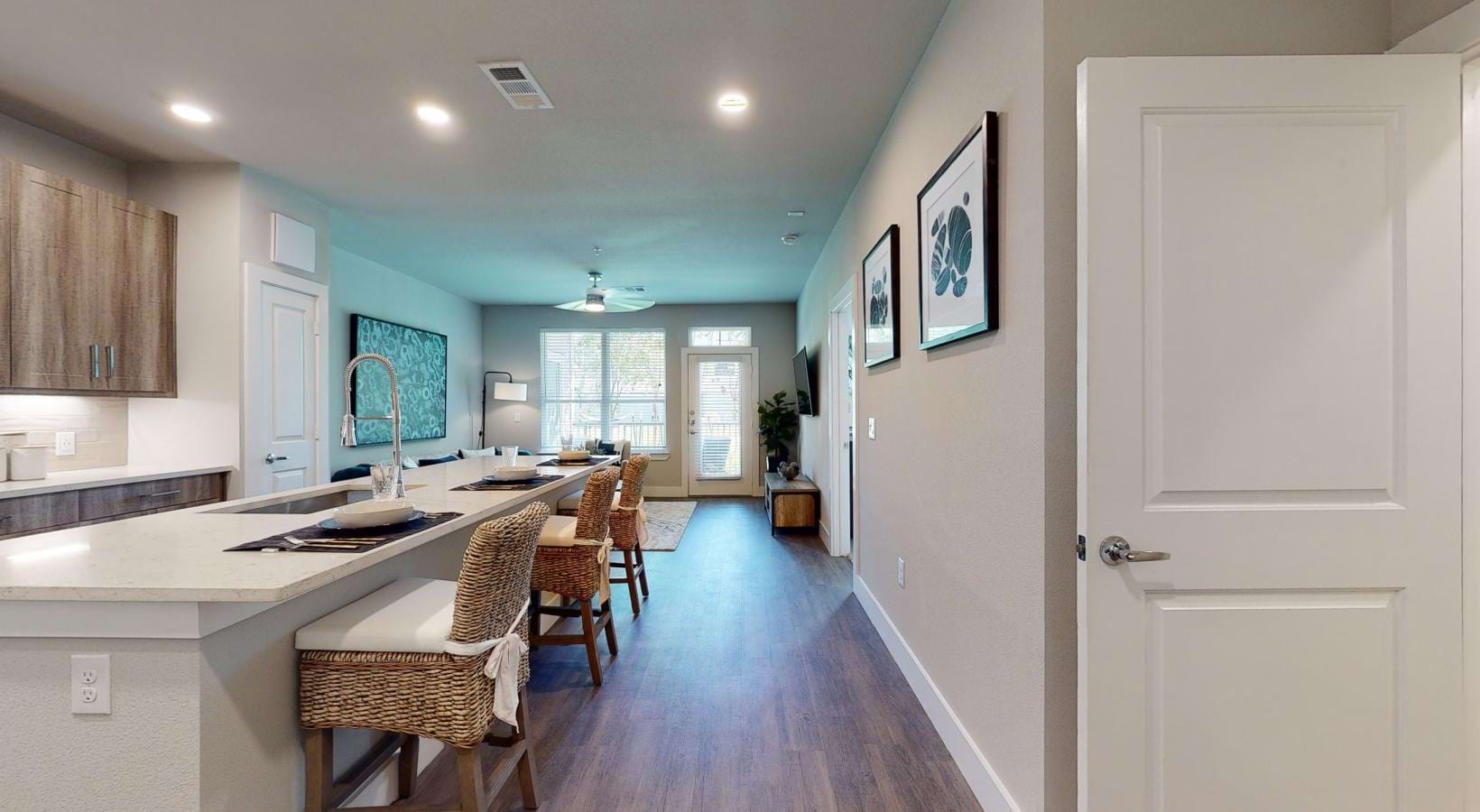 a kitchen with an island and chairs leading into a living area
