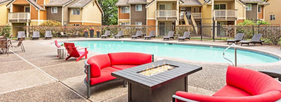 A pool surrounded by red chairs and a concrete floor.