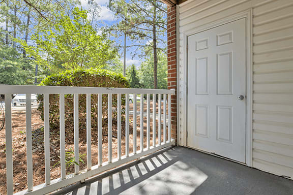 A white door is on the right side of a white fence.