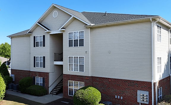 A two-story apartment building with a red brick base and beige siding.