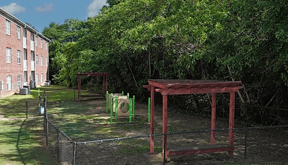 A playground with a red swing set and green slide.