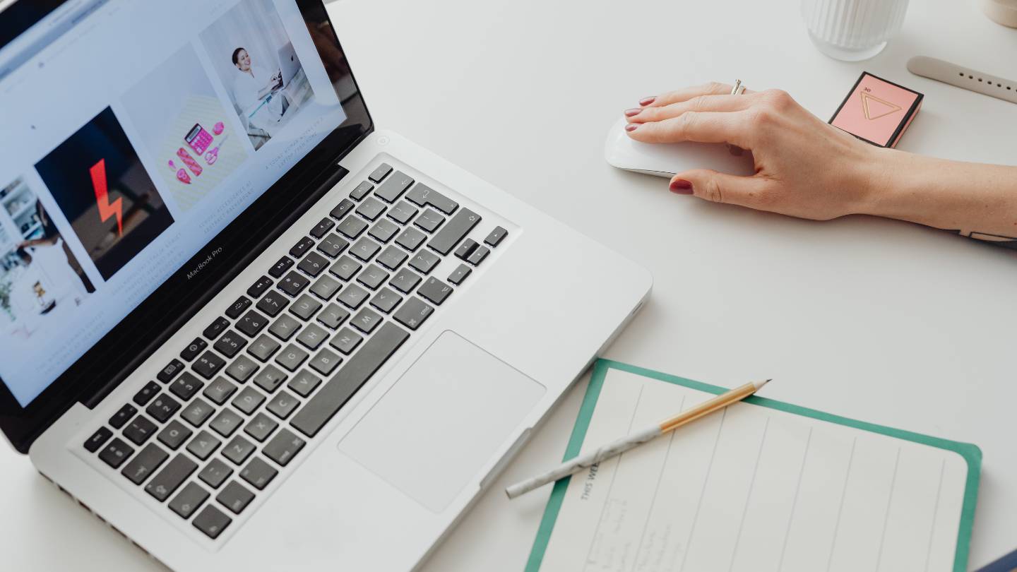 a hand moving a mouse for a laptop sitting on a table