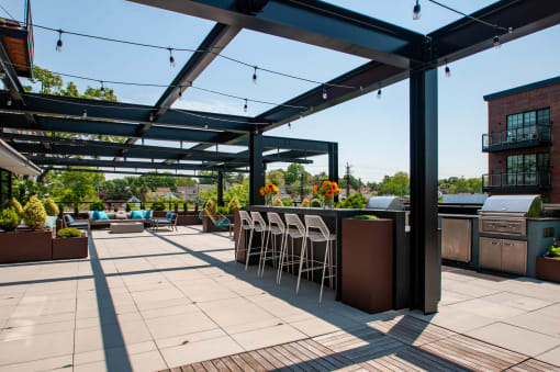 a patio with a bar and chairs under a roof
