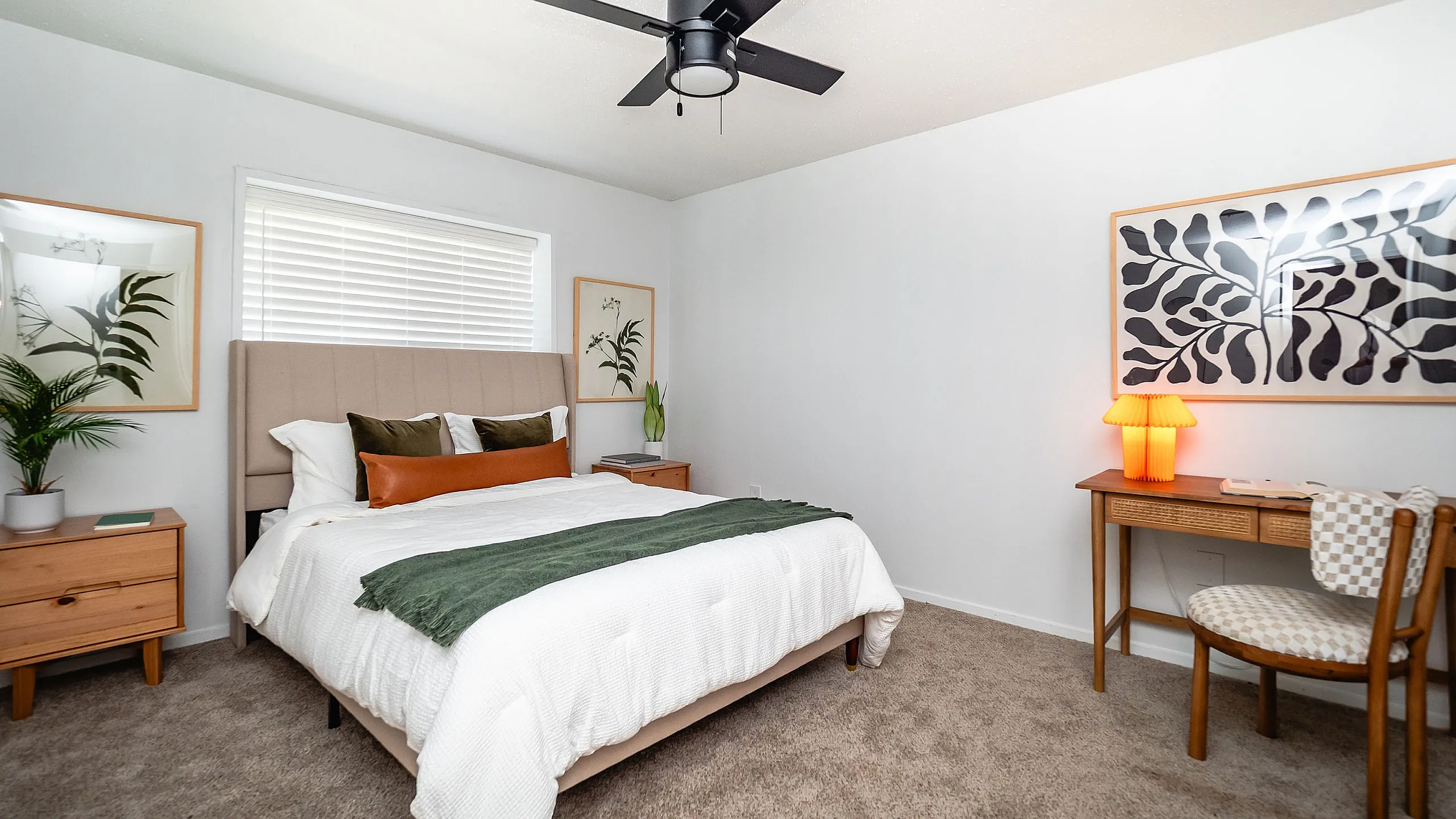 Inviting bedroom with contemporary decor, featuring a cozy bed, elegant side tables, and stylish wall art illuminated by a warm lamp.