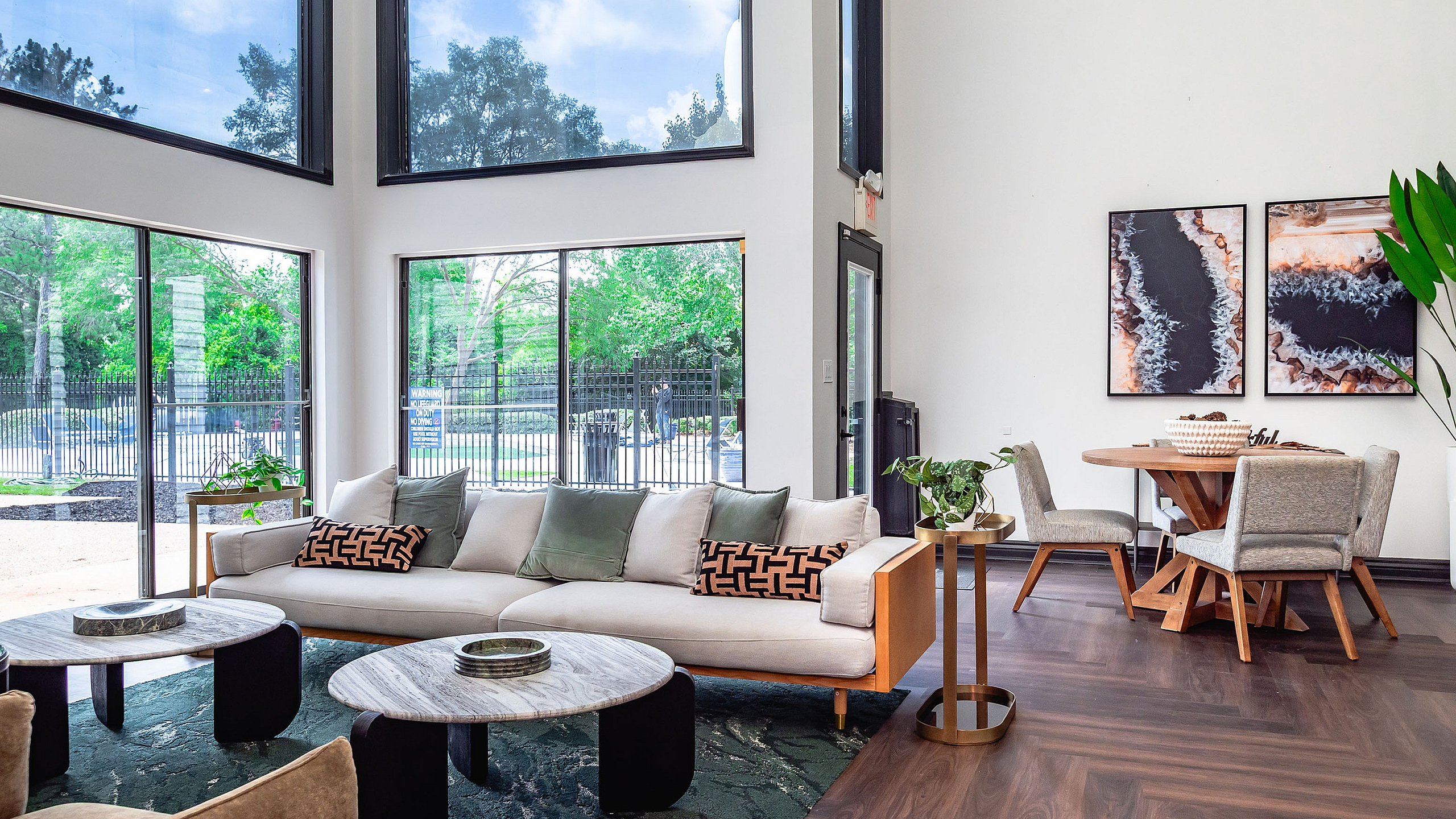 Bright and inviting living area with large windows, stylish furniture, and modern decor, featuring comfortable seating and a chic dining space with nature views.