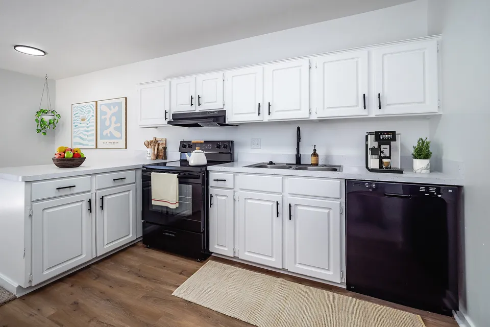 Charming modern kitchen with sleek white cabinets, elegant black appliances, and stylish decor.