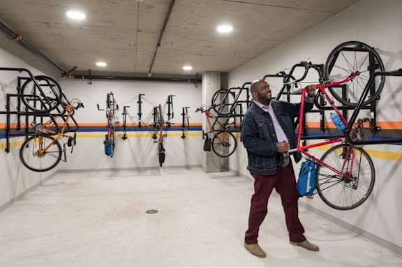 A man holding a red bike in a bike storage room.