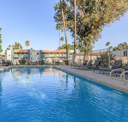 A large swimming pool surrounded by a fence and trees.at Riviera Park, Chandler
