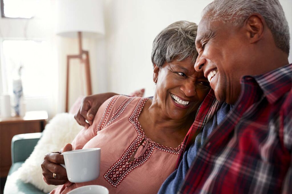 Couple embracing on the couch while drinking coffee