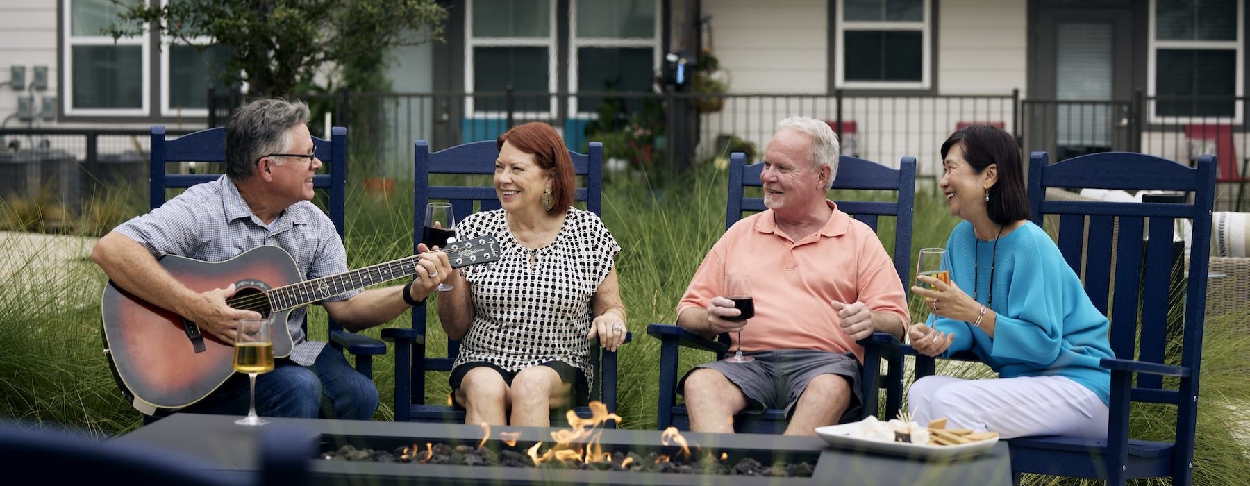 people sitting around fire and a man playing a guitar