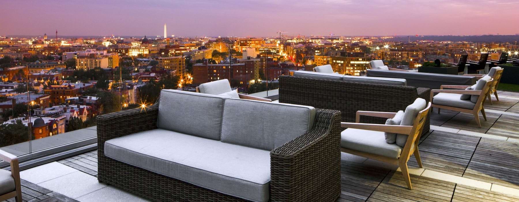 a deck with a table and chairs overlooking a city at night