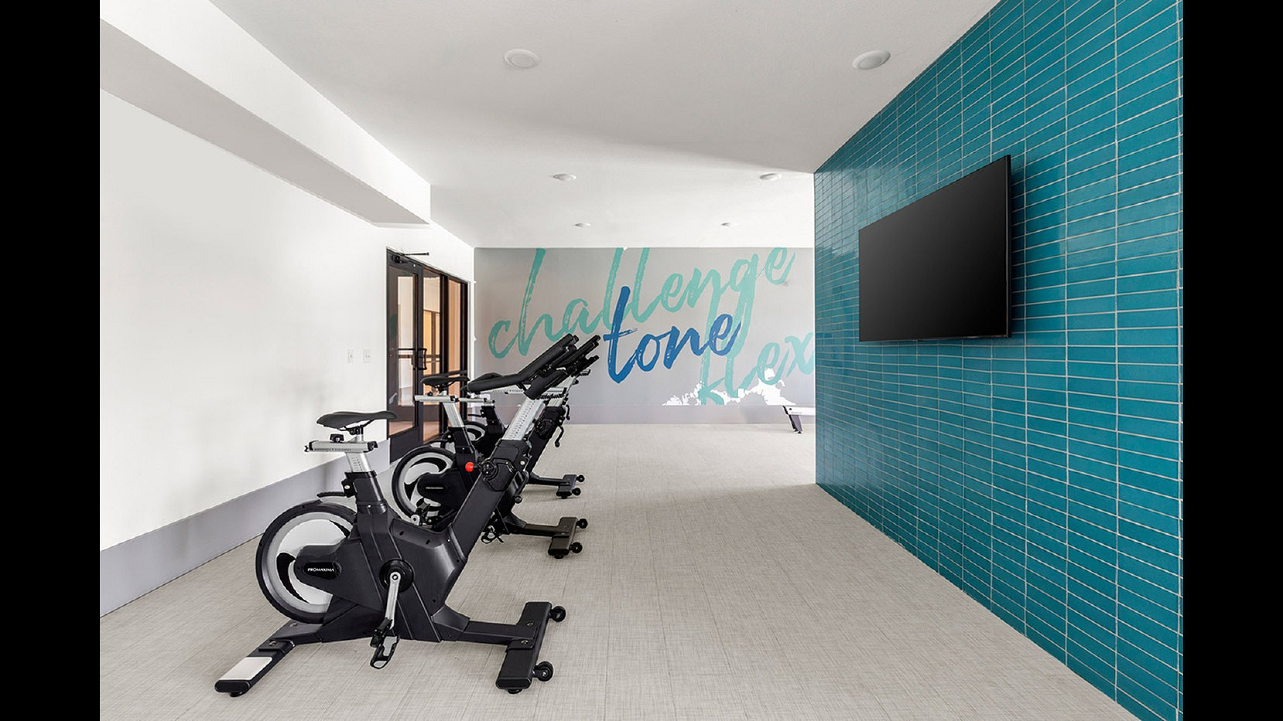 Contemporary fitness room with sleek stationary bikes, vibrant blue accent wall, and motivational artwork, ideal for energetic workouts.
