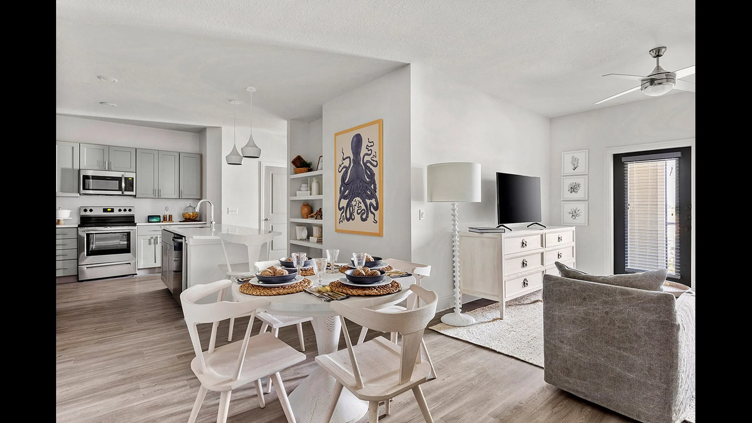 Modern open-concept living space with sleek kitchen, stylish dining area, and cozy lounge. Natural light enhances the elegant decor and contemporary furnishings.