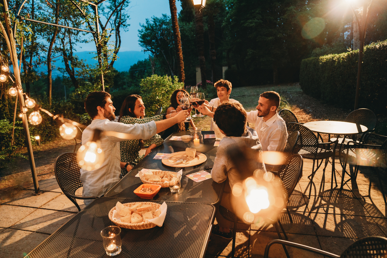 A group of friends raising their glass together while eating dinner together