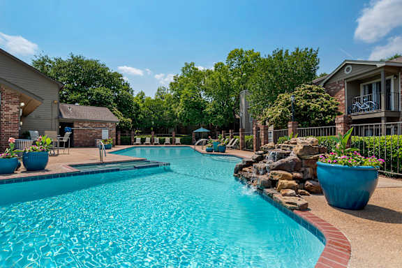 A swimming pool surrounded by a stone wall and potted plants at Pear Orchard, Ridgeland, MS