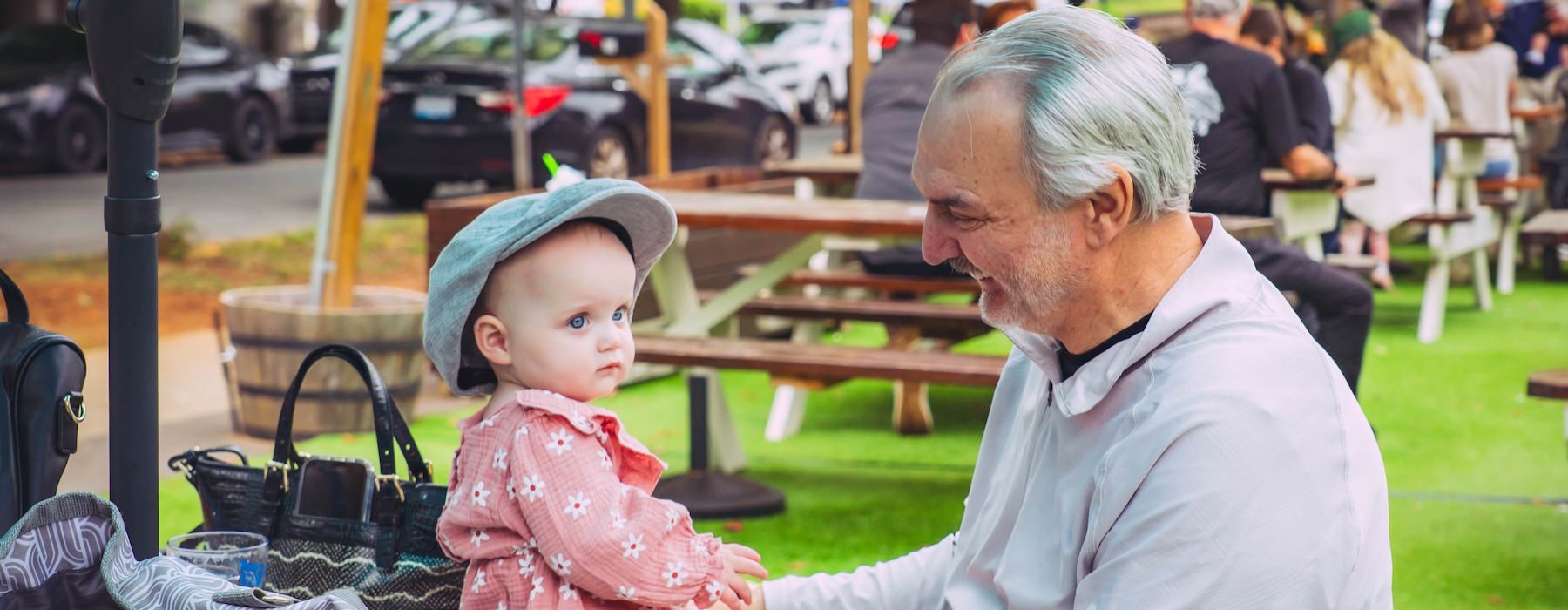a man and toddler sit on a bench outside
