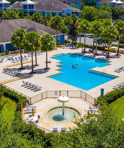 A large swimming pool surrounded by trees and a fountain.