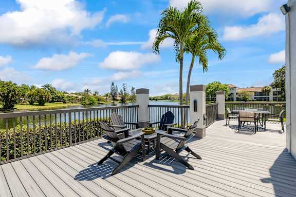 A wooden deck with a table and chairs overlooking a body of water at Waterview at Coconut Creek, Florida