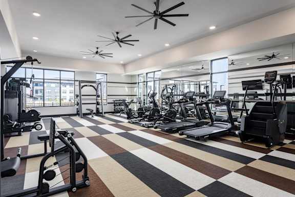 A gym with a variety of equipment including treadmills, weights, and exercise machines.