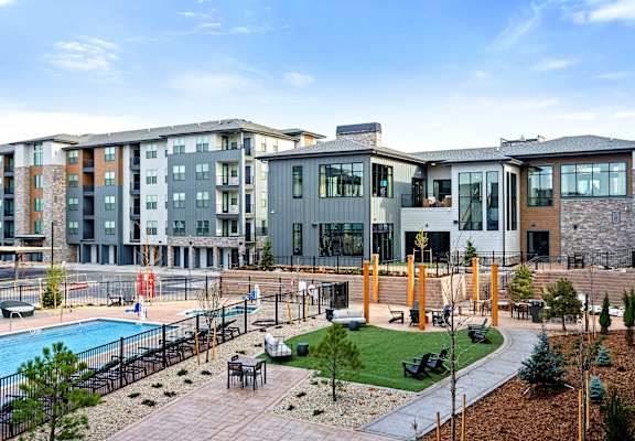 A modern apartment complex with a pool and outdoor seating area.