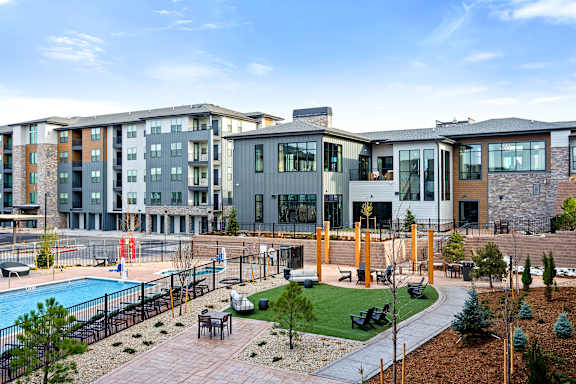 A modern apartment complex with a pool and outdoor seating area.