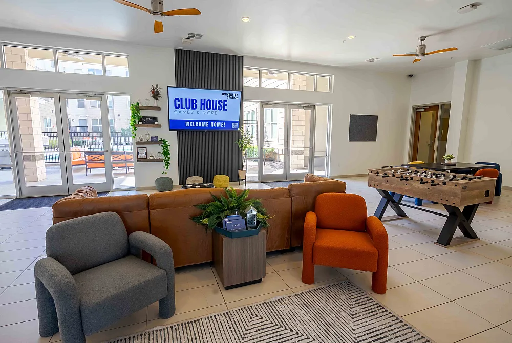 Inviting clubhouse lounge with cozy seating, vibrant decor, and a fun foosball table, perfect for social gatherings and relaxation.