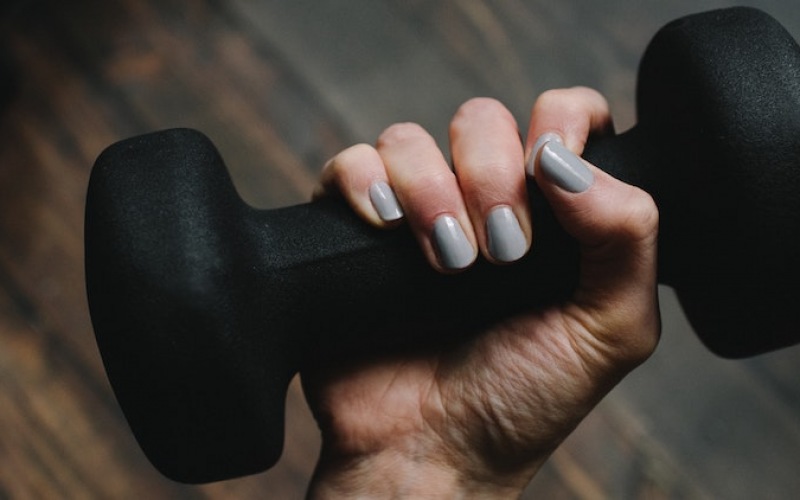 lifestyle image of a woman's hand holding a free weight