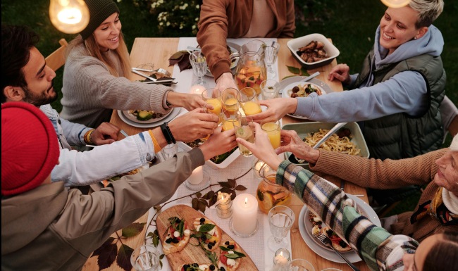 Friends at a table with their glasses touching in the center.