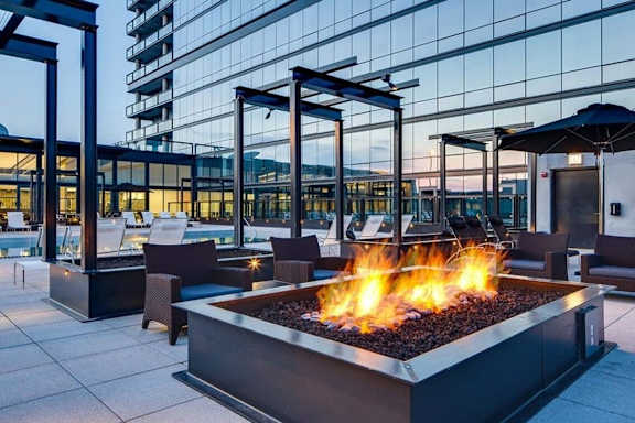 A fire pit sits in the middle of a patio with chairs around it.