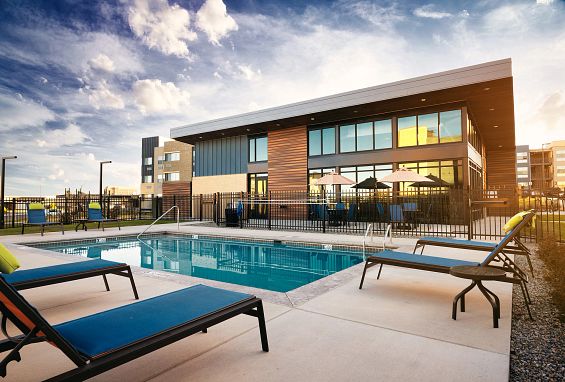 alt="Relaxing pool deck with loungers and table seating"