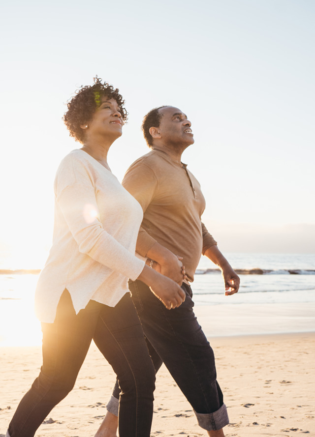 couple walking on beach holding hands at sunset