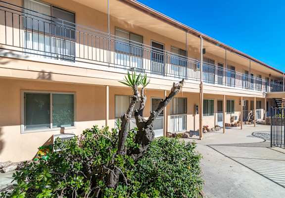 A building with a balcony and a tree in front.