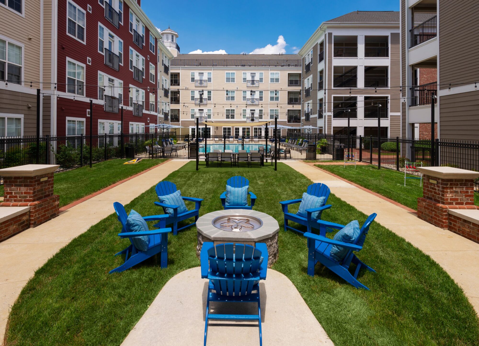 Outdoor seating area in courtyard with 6 blue chairs around a firepit