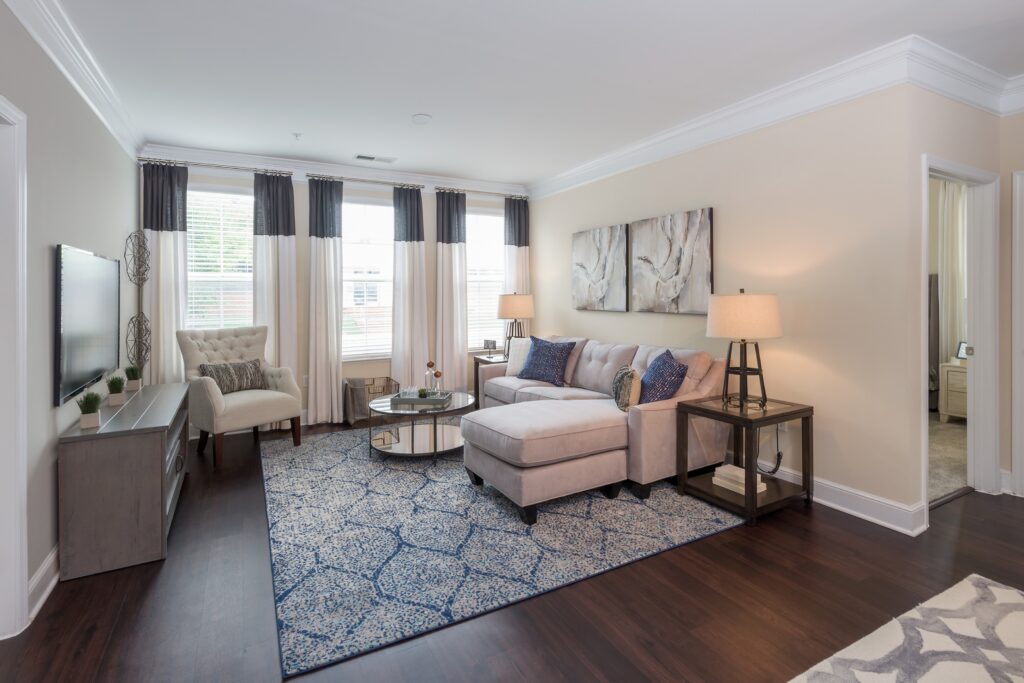 Living room with natural light, grey sectional sofa, and white wingback chair.