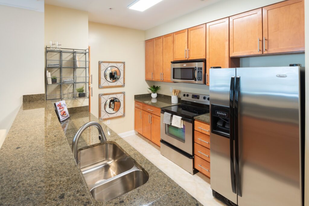 Kitchen with gray counter tops, wooden cabinets, and silver appliances.