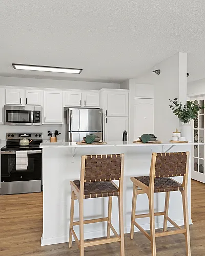 Modern kitchen design with sleek white cabinetry, stainless steel appliances, and inviting breakfast bar with chic woven chairs.