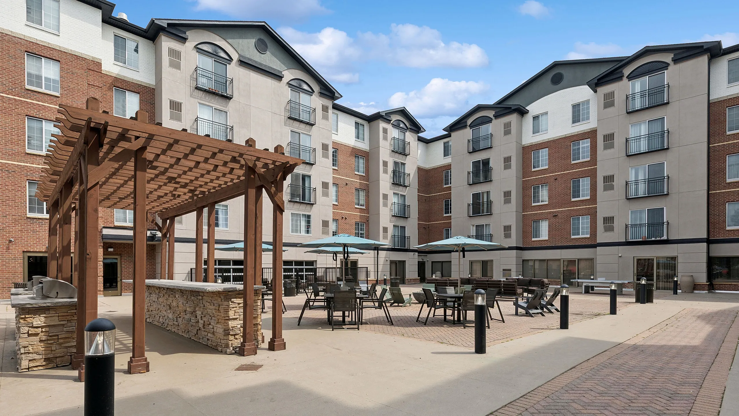 Charming apartment courtyard featuring elegant pergola, outdoor seating, and modern brick architecture—perfect for social gatherings.