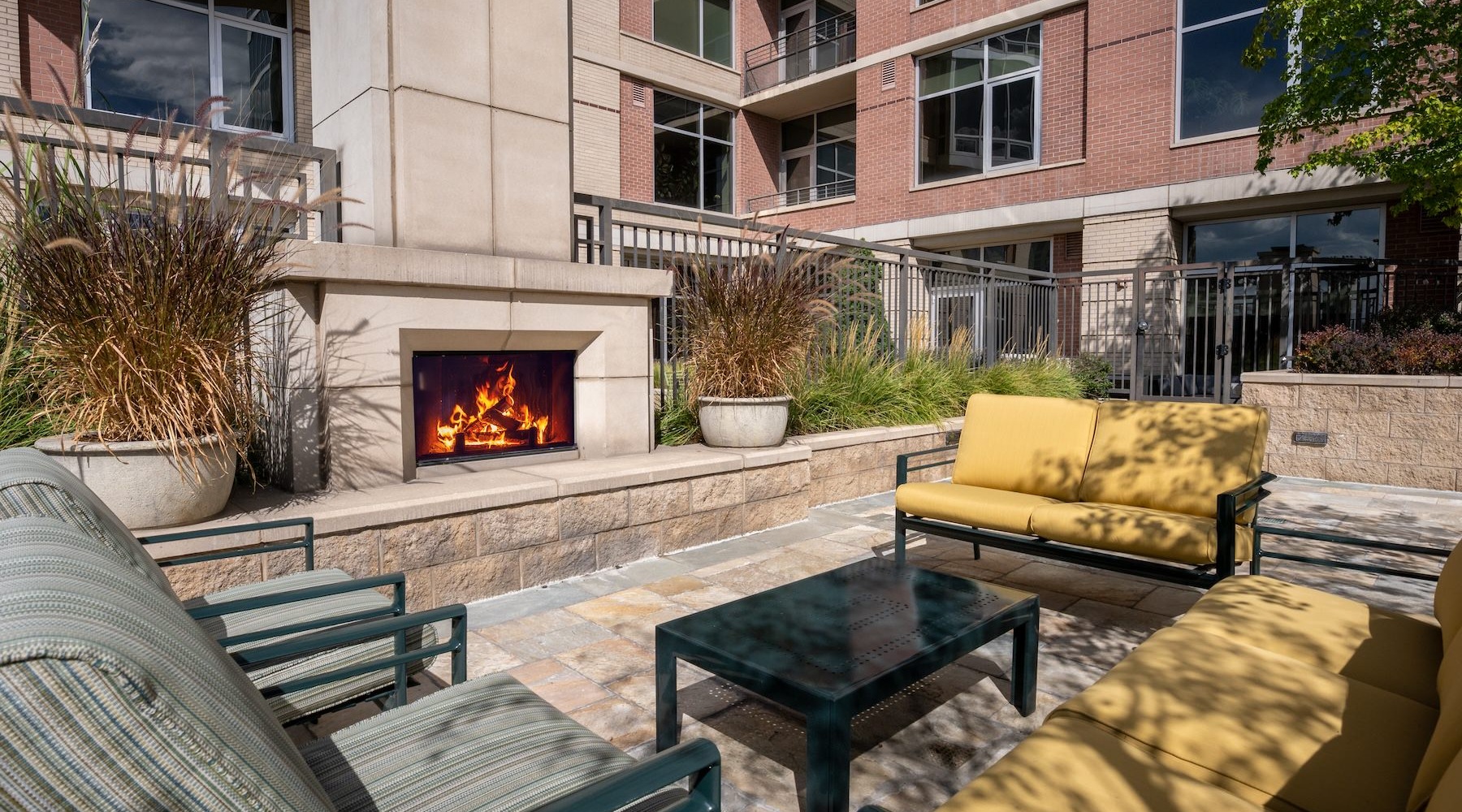 an outdoor lounge with a fireplace and chairs