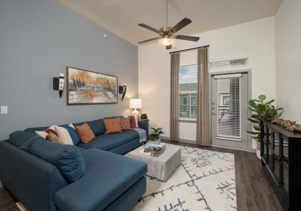 Stylish living room with large couch and ceiling fan at Orleans at Fannin Station in Houston, Texas