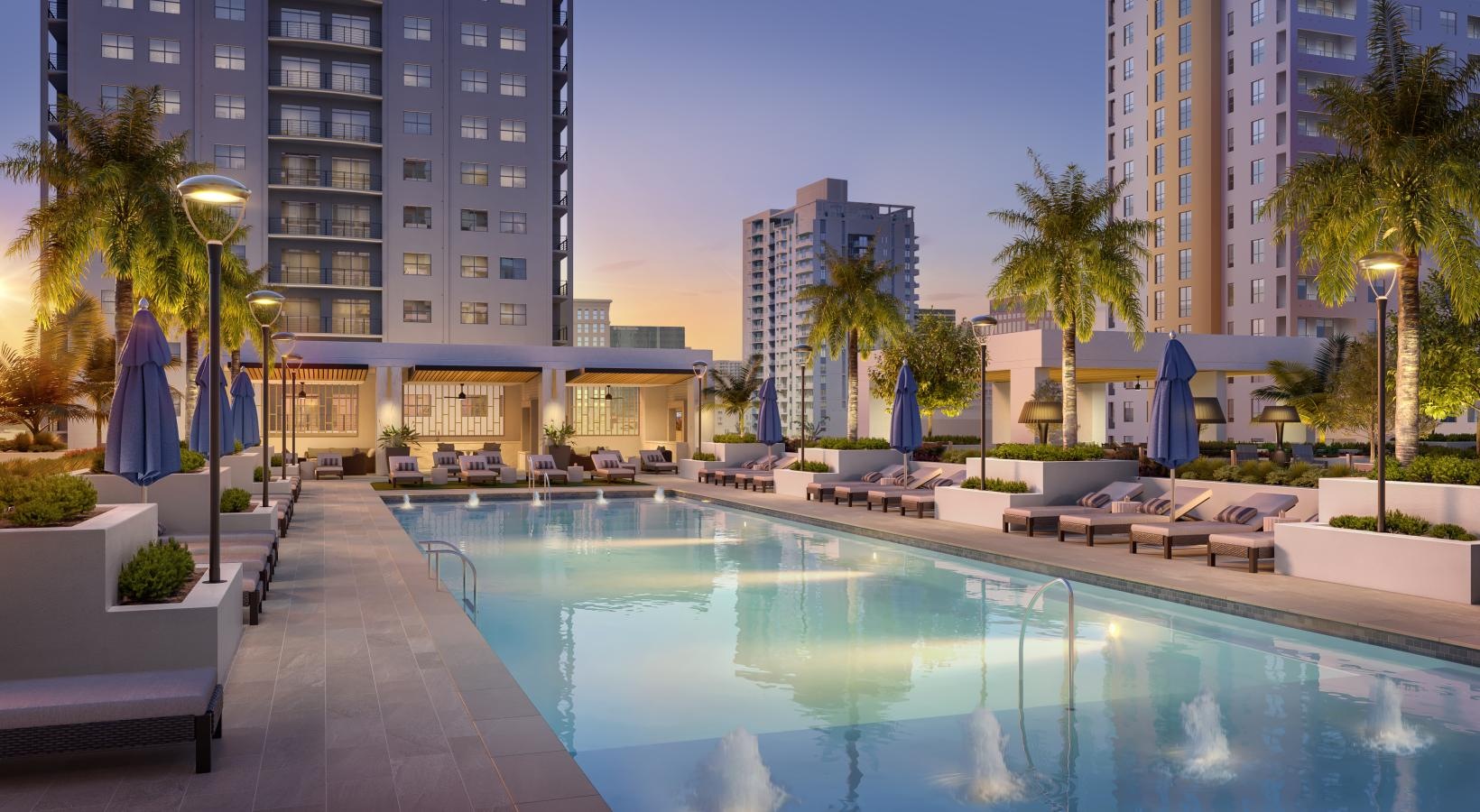 a pool with lounge chairs and umbrellas by a building