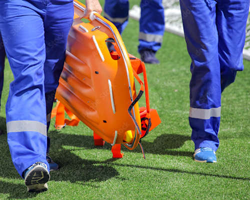 A person in blue pants and shoes is carrying an orange helmet.