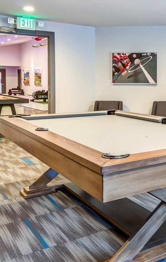 A pool table in a room with a blue wall and a picture of a pool table. at Brackett Apartments, Edmonds, WA, 98020