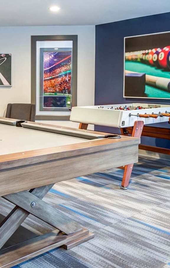 A pool table in a room with a blue wall and a picture of a pool table. at Brackett Apartments, Edmonds, WA, 98020
