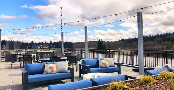 a rooftop patio with blue couches and chairs and string lights