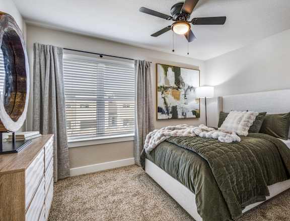 A bedroom with a bed, dresser, and a ceiling fan.