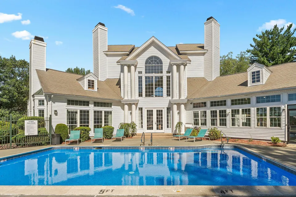 Elegant resort-style clubhouse with a sparkling blue pool, surrounded by luxurious loungers and lush landscaping.